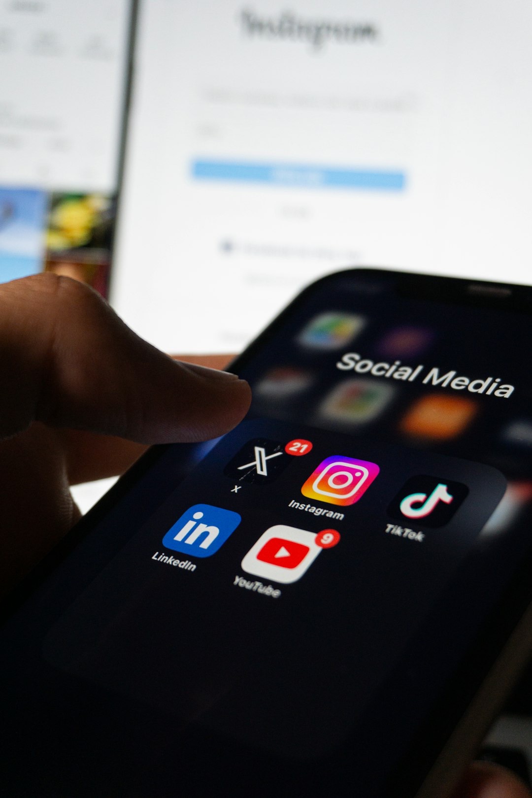 Thumb hovering over smartphone apps for social media marketing.